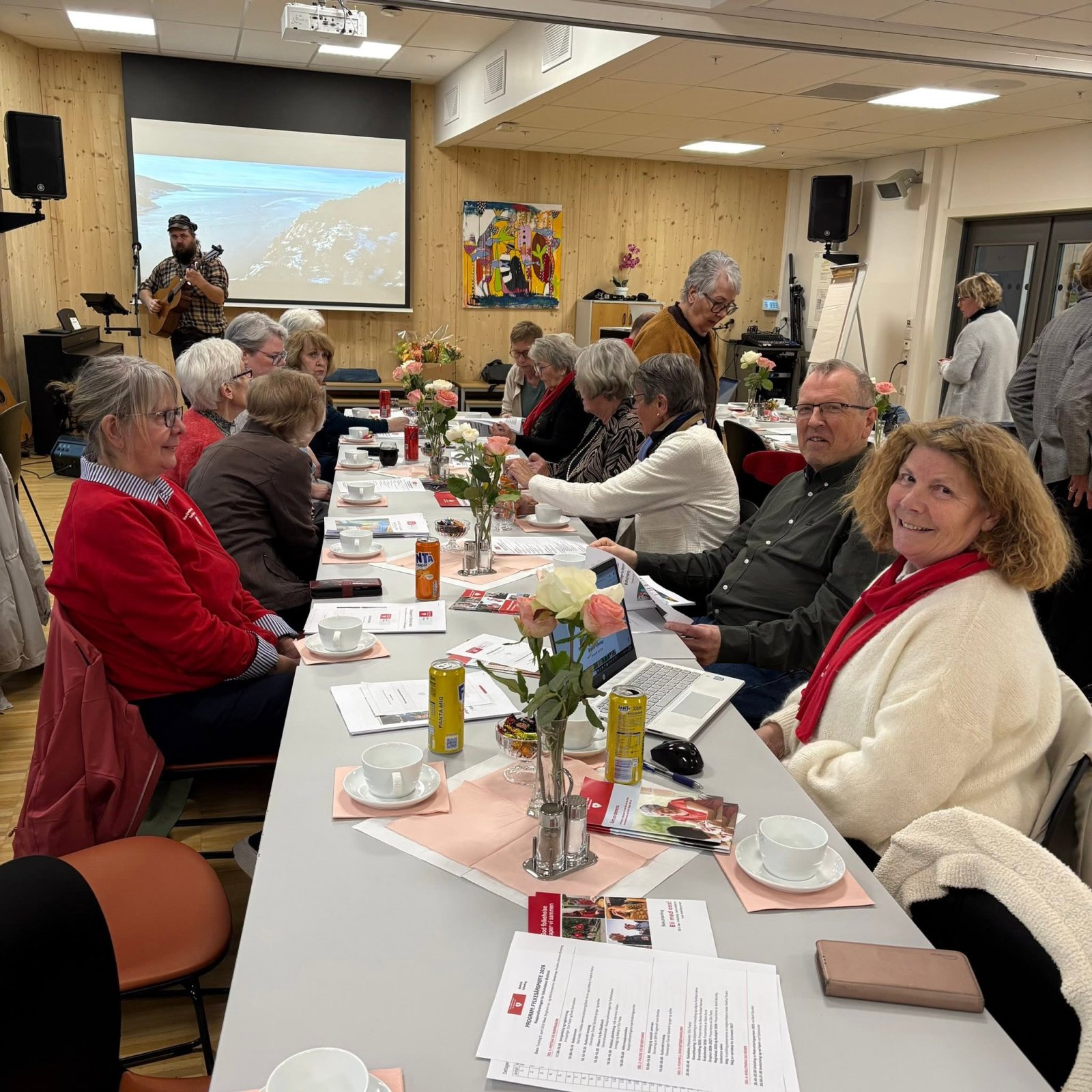 Deltakerne rundt bordene under årsmøtet, med visesanger på scenen